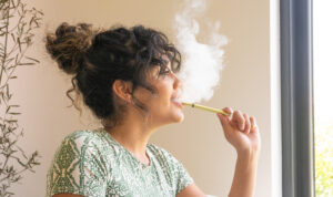 A woman vaping by a window