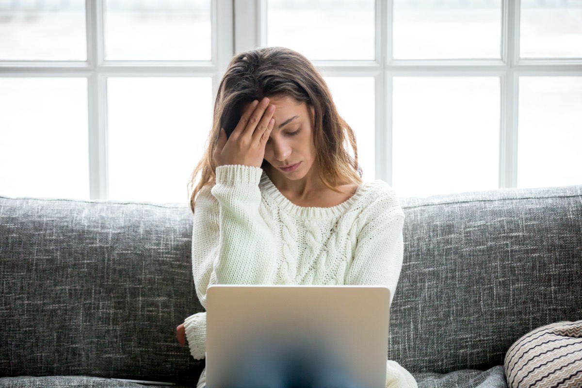 Frustrated sad woman feeling tired worried about problem sitting on sofa with laptop, stressed depressed girl troubled with reading bad news online, email notification about debt or negative message