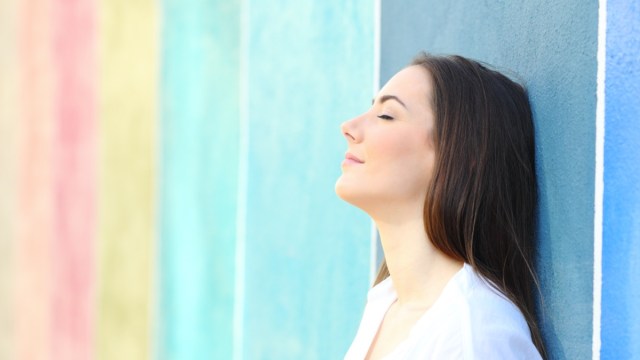 portrait of a relaxed woman resting leaning on a colorful wall in the street