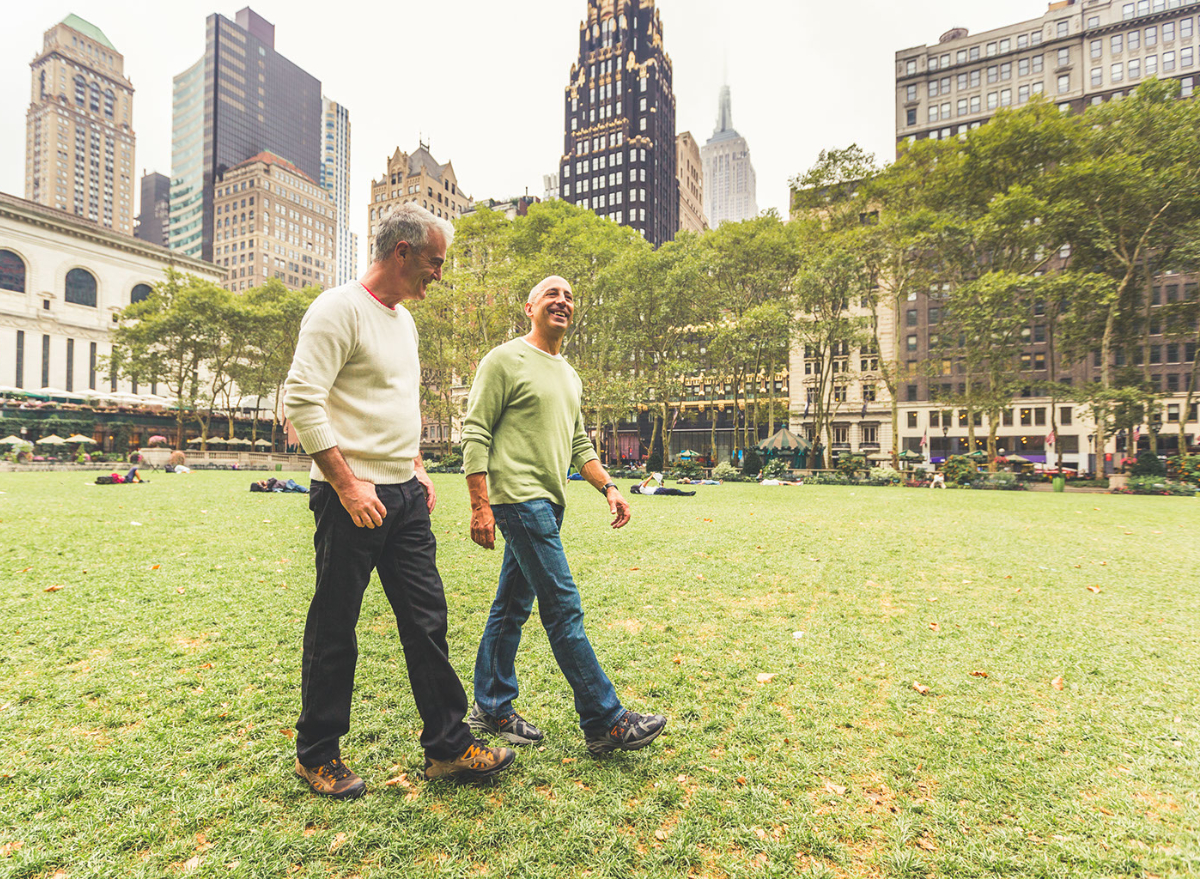 two men walking together in an urban park with buildings behind them