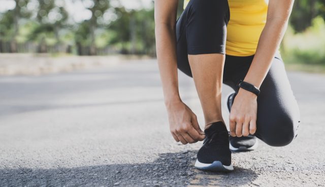 young woman in running clothes lacing sneakers