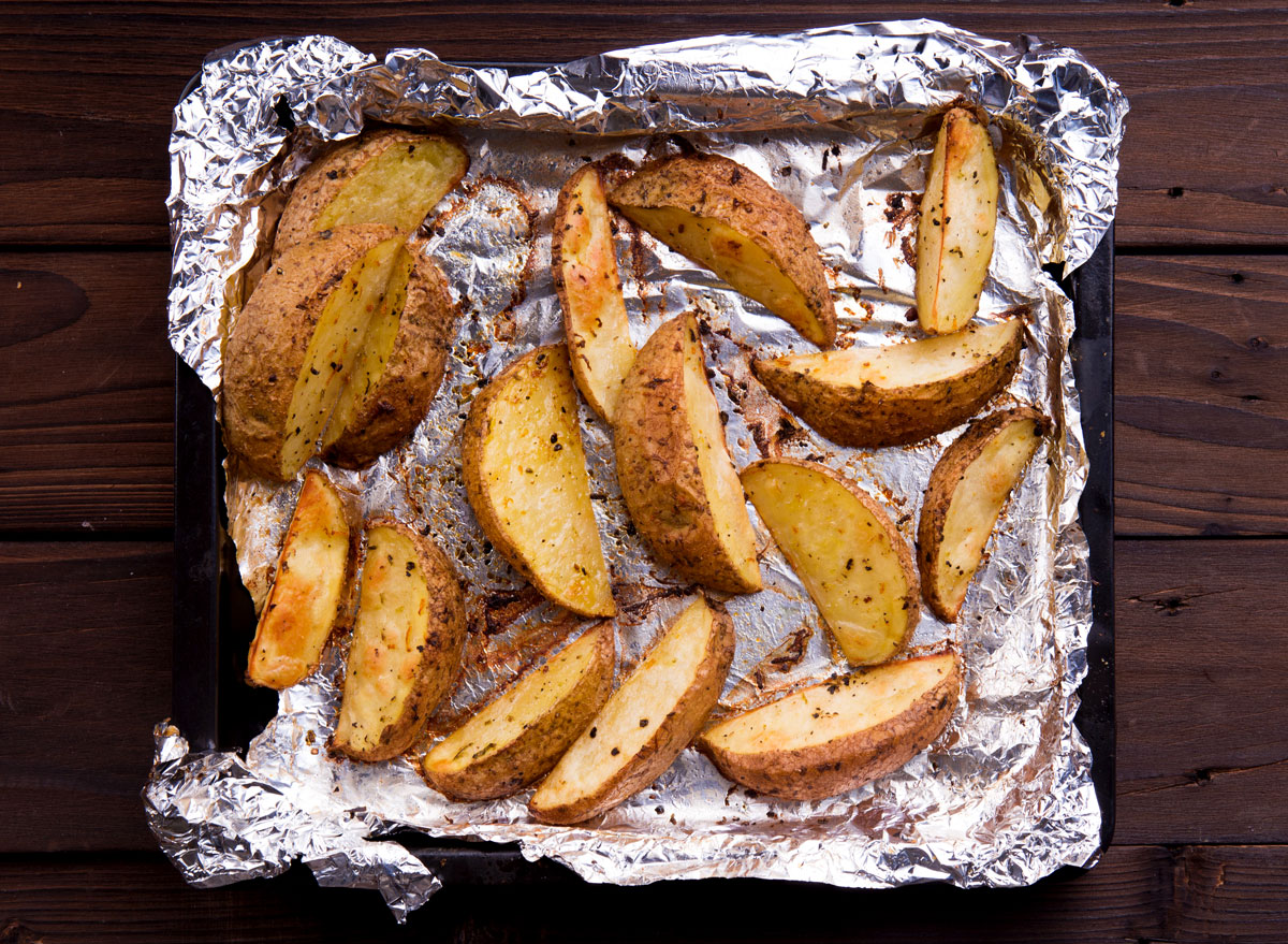 Roasted baked potato wedges on aluminum foil lined baking tray