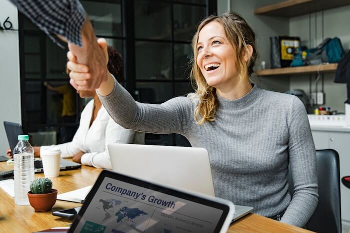 woman smiling shaking hands how to be a nicer person