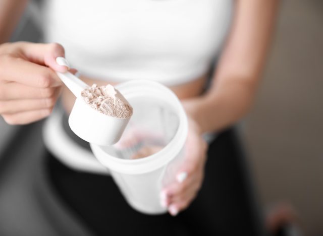 close-up woman's hand holding muscle-building protein powder to gain weight