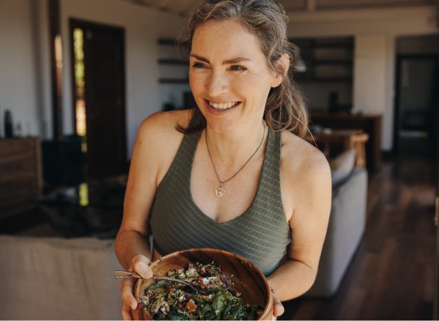 mature woman holding bowl of salad at home, easy ways to lose weight when you're just starting out