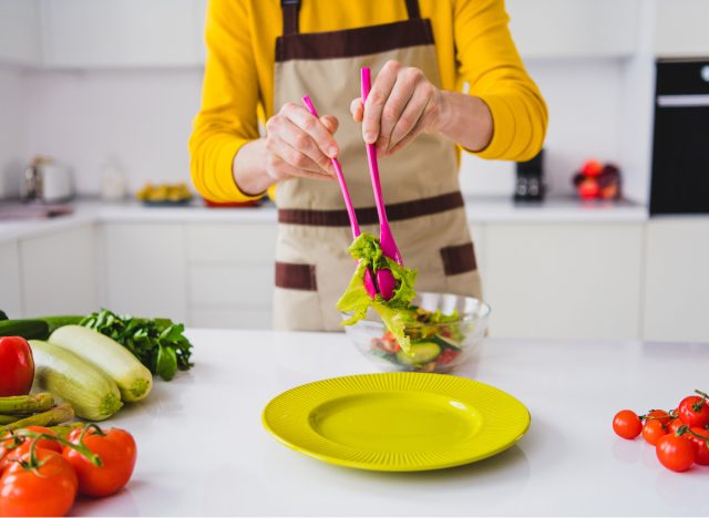 close-up putting salad on plate in kitchen