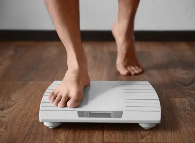 close-up man stepping onto scale