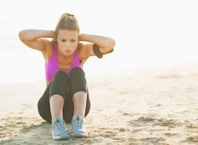 woman doing sit-ups, concept of HIIT workouts to melt belly fat