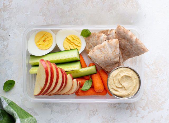 box of hummus, carrots, apples, eggs, and pita bread