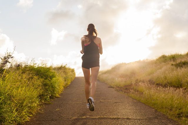 woman jogging uphill on sunny day