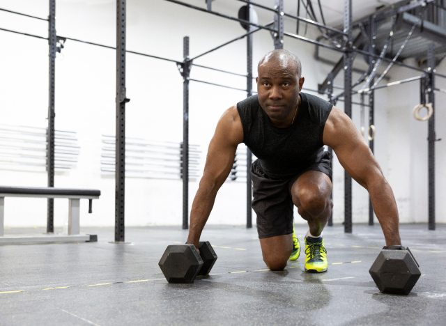 man in 40s works out with weights in a gym