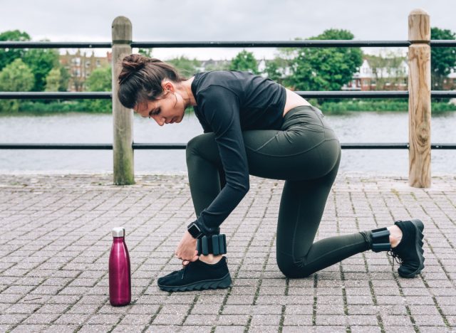 woman tying sneakers during walk with ankle weights