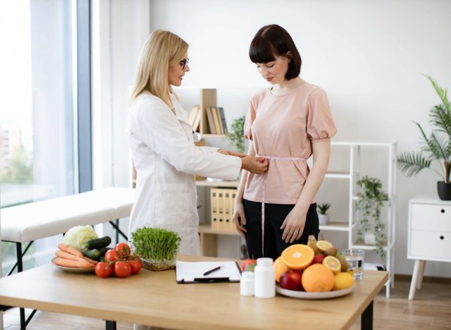 doctor or nutritionist measuring a patient's waistline