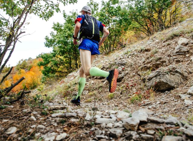 man jogging on trail with rucksack