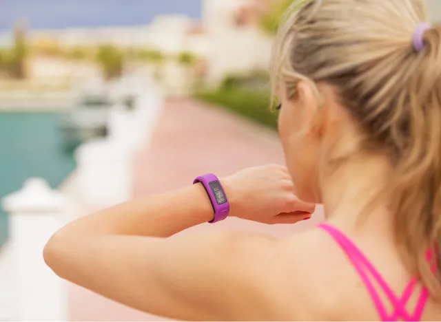 close-up woman checking her watch fitness tracker as she's walking for weight loss