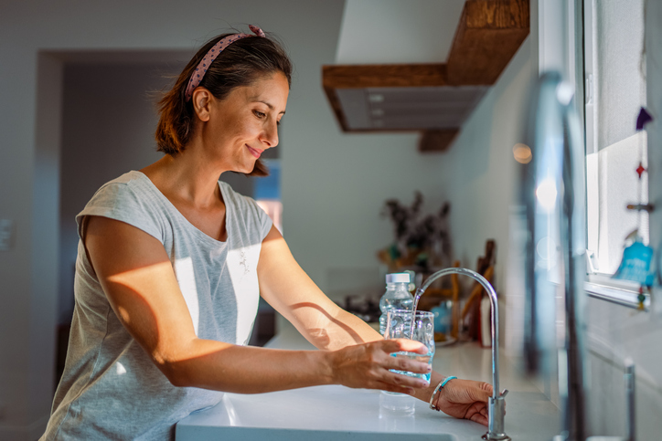 woman pouring water into cup | Why Are Glucose Spikes Harmful