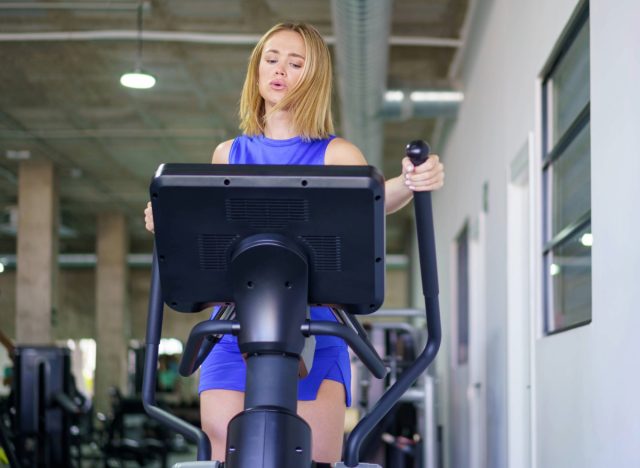 focused woman doing intense elliptical workout at the gym