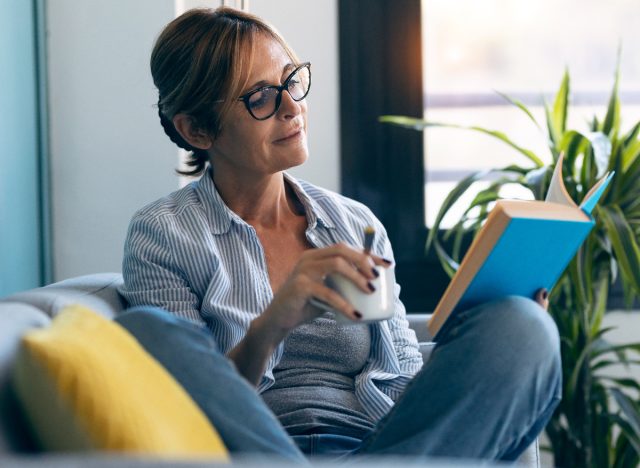 woman sitting reading book on couch