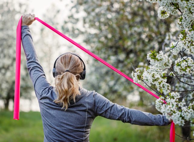 woman doing resistance band exercise outdoors, concept of resistance band workouts to stay active and fit as you age