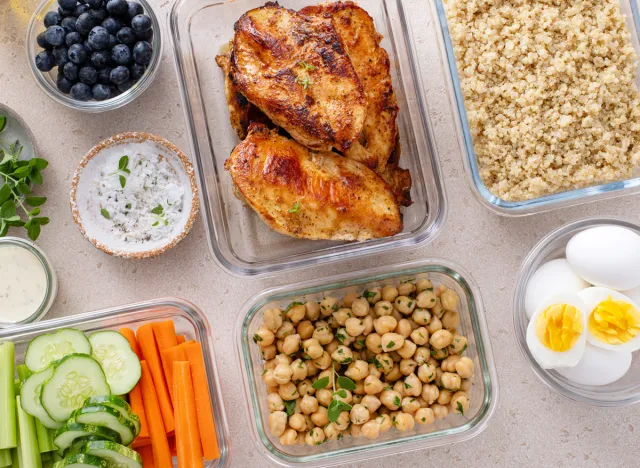 high protein meal prep concept with chicken chickpeas quinoa hard boiled eggs veggie sticks and blueberries in individual containers