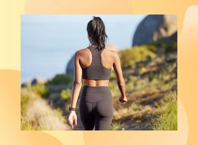 back view of fit brunette woman walking on a path by the ocean for exercise