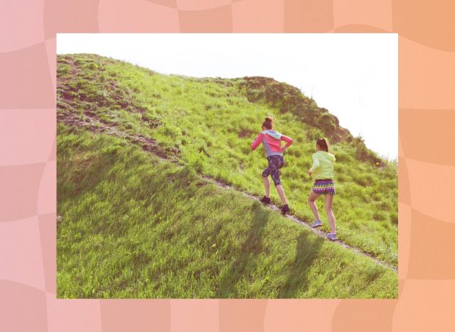 two fit female friends walking uphill, hiking for exercise on sunny day