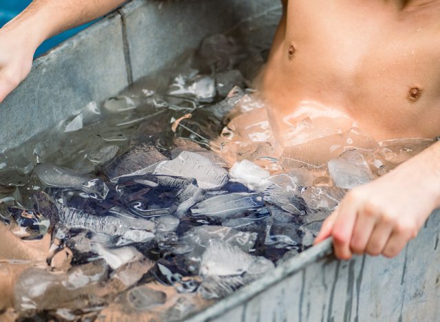 Body and hands of a boy or man ice bathing in the cold water among ice cubes in a vintage bathtub. Wim Hof Method, cold therapy, breathing techniques, yoga and meditation