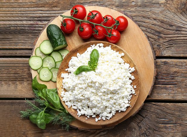 Cottage cheese, cucumber, tomatoes, sandwiches and basil on wooden table